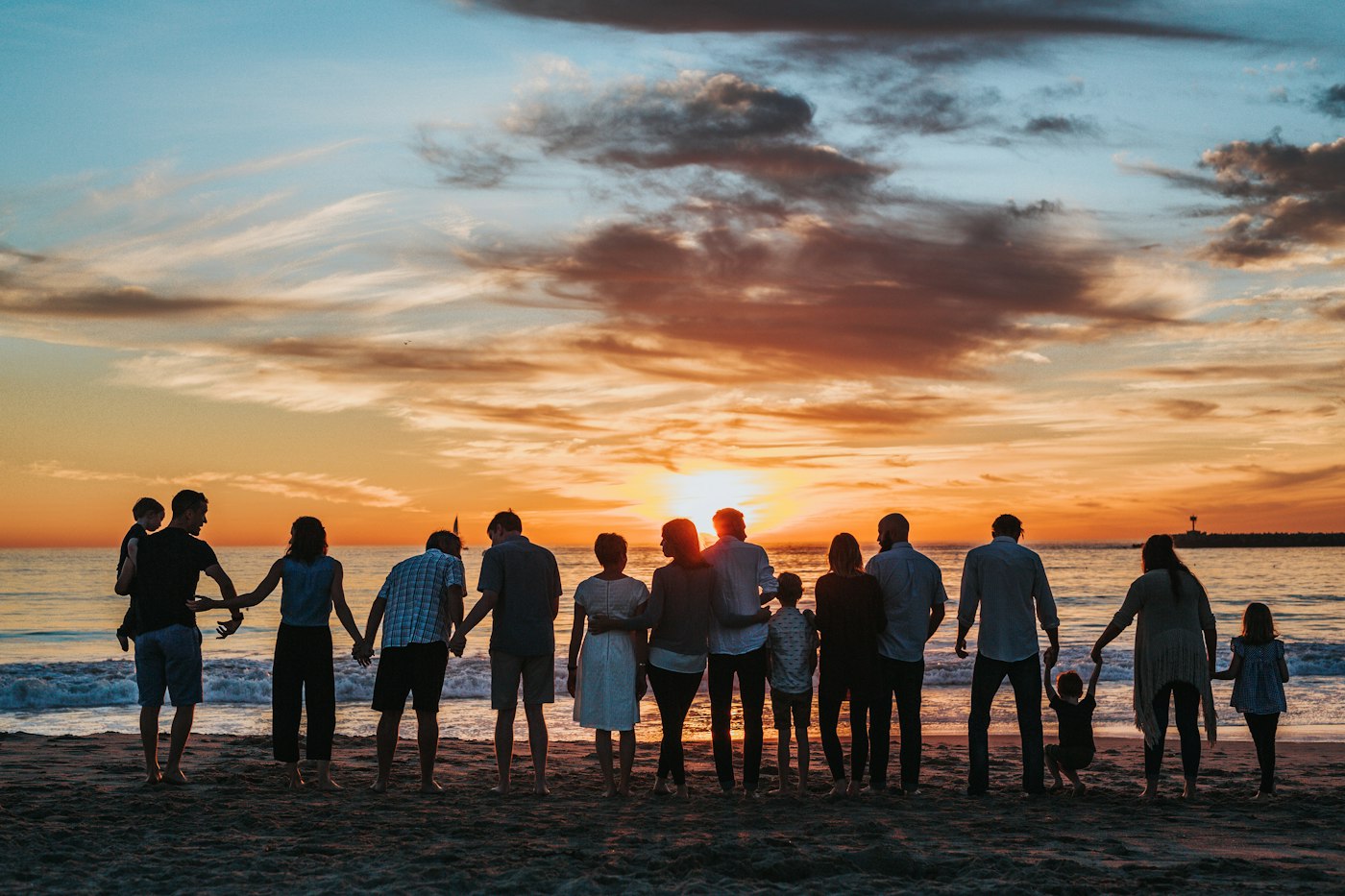 Una familia tomada de la mano frente al mar al atardecer