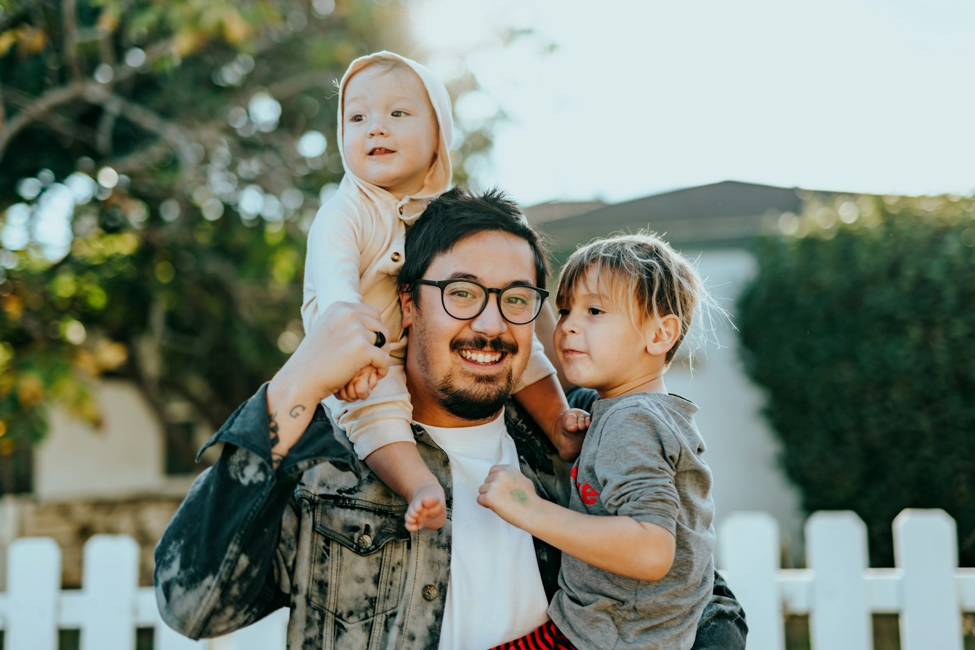 Padre sonriente cargando a sus dos hijos